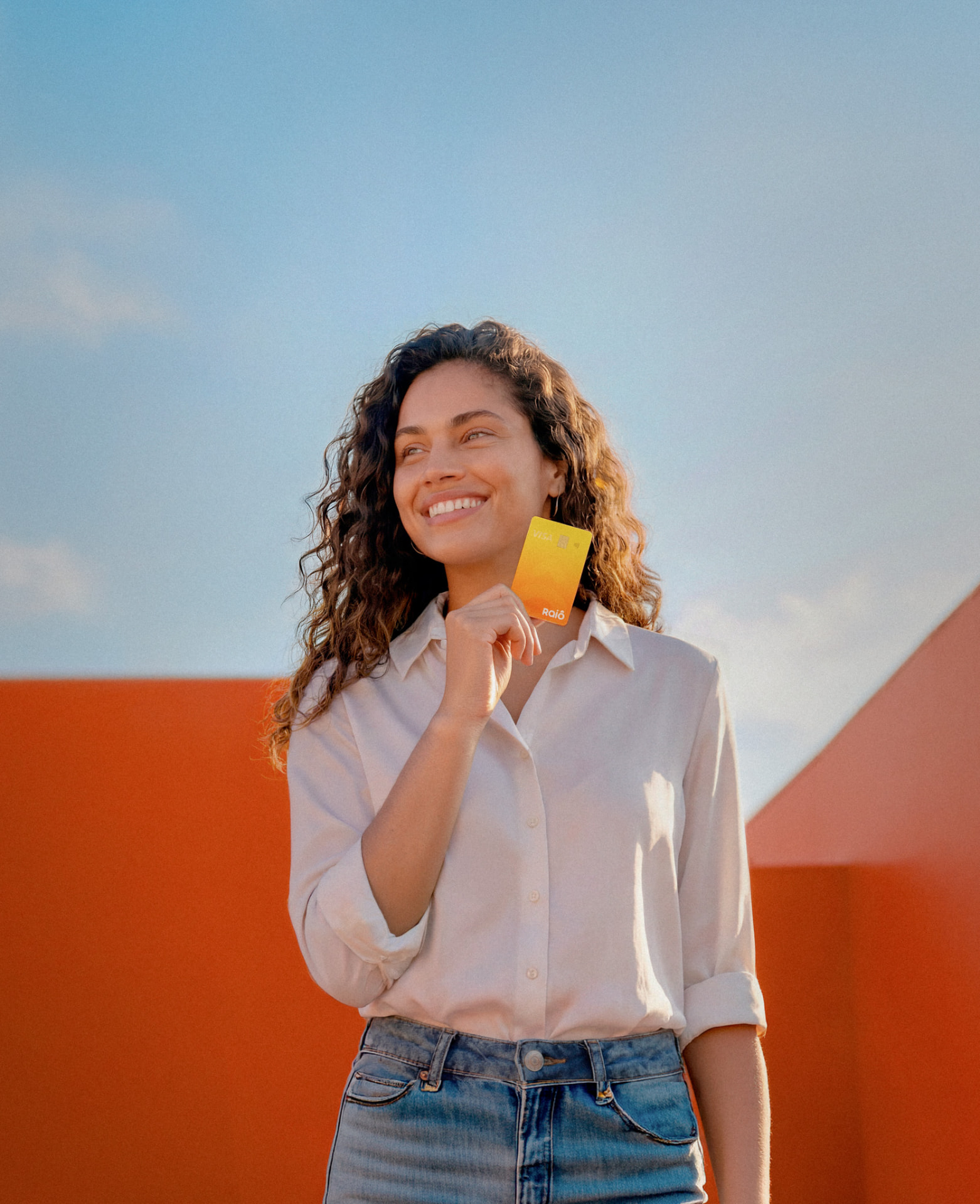 Mulher sorrindo segurando um cartão Raiô